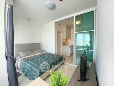 Modern bedroom with sliding glass doors and view into kitchen area, featuring stylish decor and natural light.