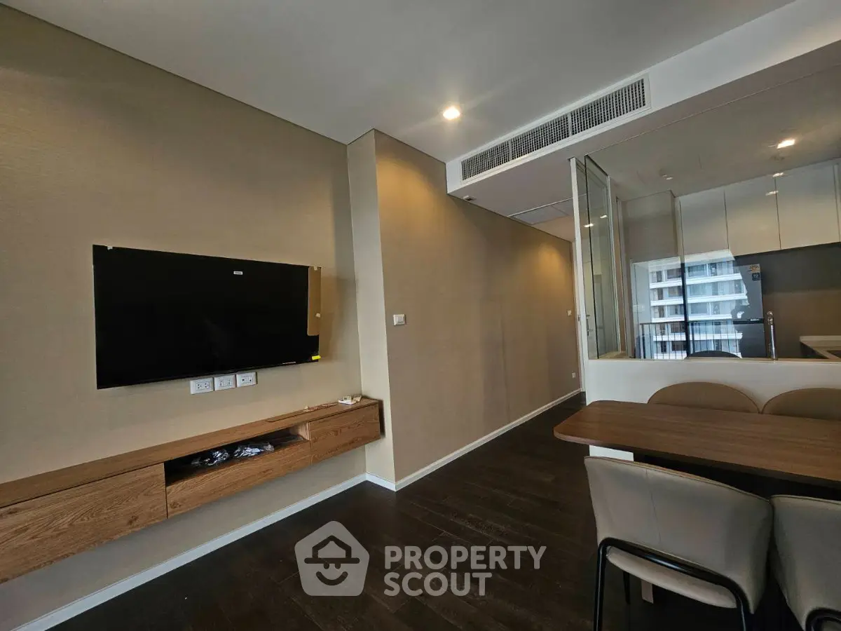 Modern living room with wall-mounted TV and sleek wooden furniture in a contemporary apartment.