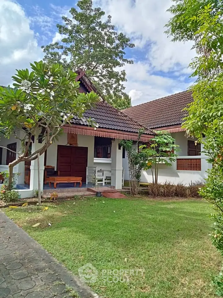 Charming traditional house with lush garden and inviting entrance in serene neighborhood.