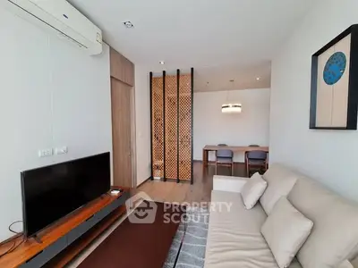 Modern living room with stylish decor and dining area, featuring a sleek TV setup and comfortable seating.