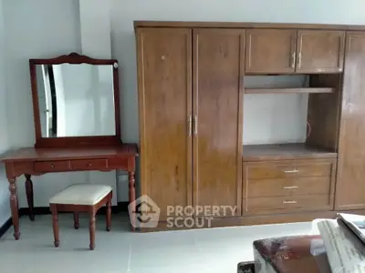 Spacious bedroom with elegant wooden wardrobe and vanity set, perfect for stylish storage solutions.