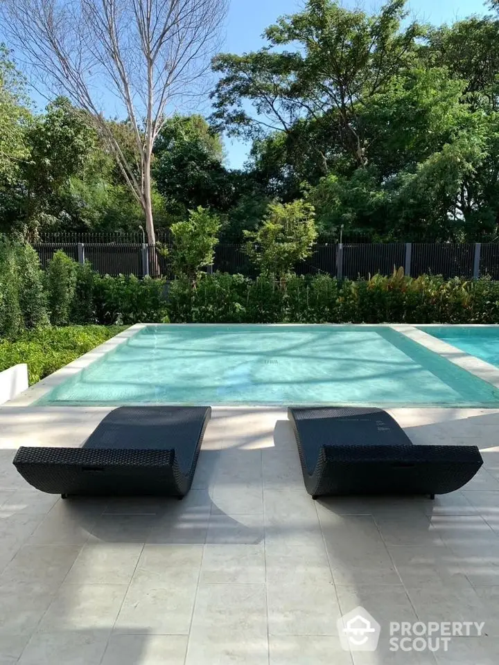 Luxurious outdoor pool area with stylish lounge chairs and lush greenery