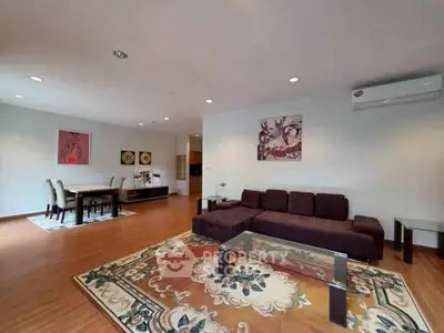 Spacious living room with elegant decor and dining area, featuring modern furniture and wooden flooring.