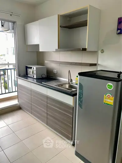 Modern kitchen with sleek cabinets, stainless steel fridge, and balcony view.
