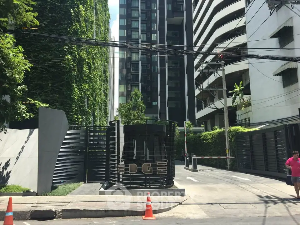 Modern building entrance with lush greenery and sleek design in urban setting.