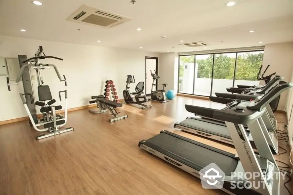 Spacious modern gym with state-of-the-art equipment and large windows offering natural light.