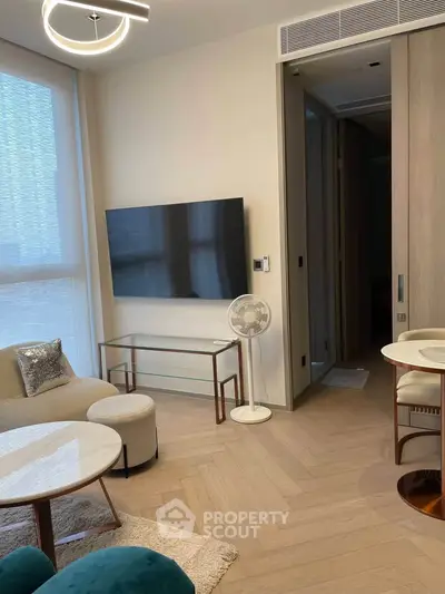 Modern living room with stylish furniture and large TV, featuring elegant lighting and natural light from large windows.