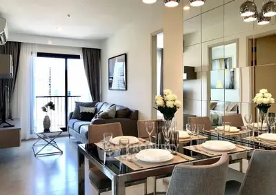 Modern living room with elegant dining area and mirrored wall, featuring stylish decor and natural light.