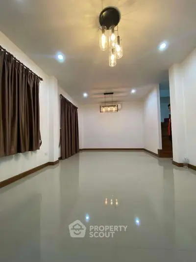 Spacious living room with modern lighting and large windows, perfect for family gatherings.