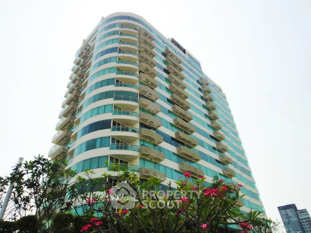 Modern high-rise building with curved balconies and lush greenery