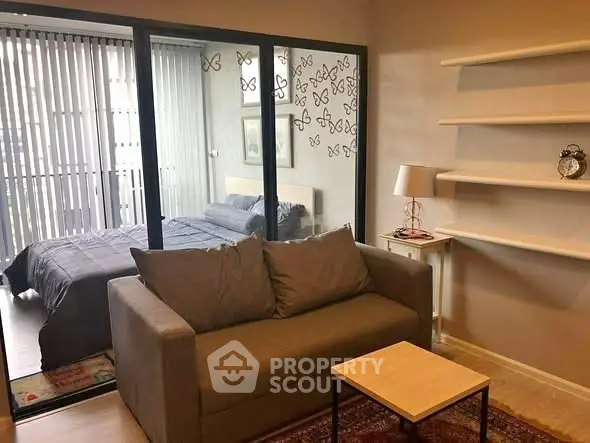 Cozy living room with a view into a modern bedroom through glass partition, featuring stylish decor.