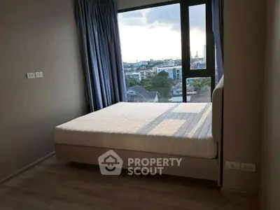 Modern bedroom with large window offering stunning city view and natural light.