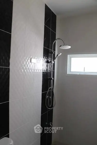 Modern bathroom with sleek shower and stylish black and white tiles.