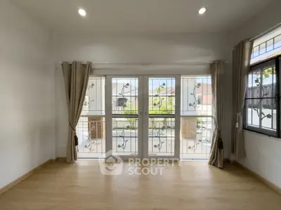 Spacious living room with large windows and elegant curtains, offering a bright and airy atmosphere.