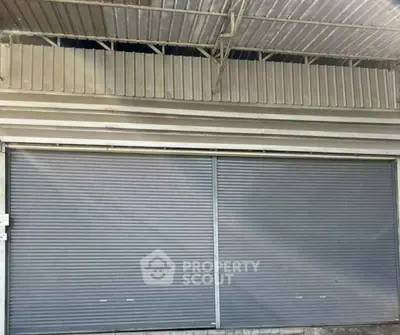 Commercial property with metal shutters and corrugated roof, ideal for business setup.
