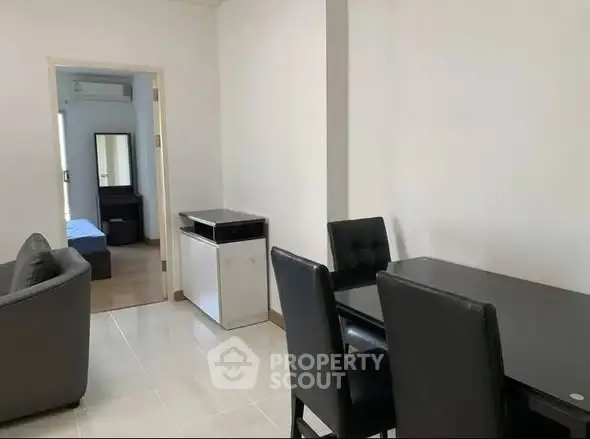 Modern dining area with sleek black furniture and open view to living room.