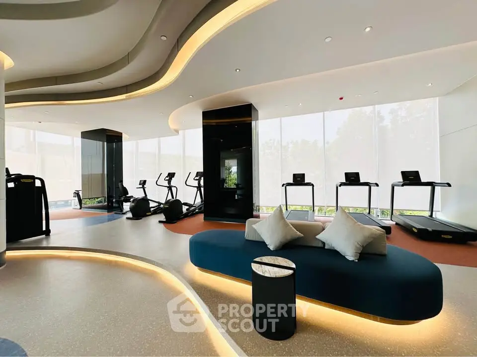 Luxurious modern gym with state-of-the-art equipment and stylish seating area.