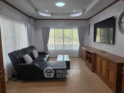 Spacious living room with modern sofa and large TV, perfect for relaxation.