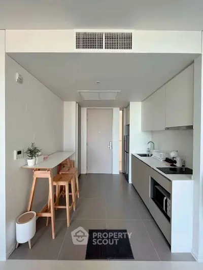 Modern compact kitchen with sleek white cabinets and breakfast bar in a stylish apartment.