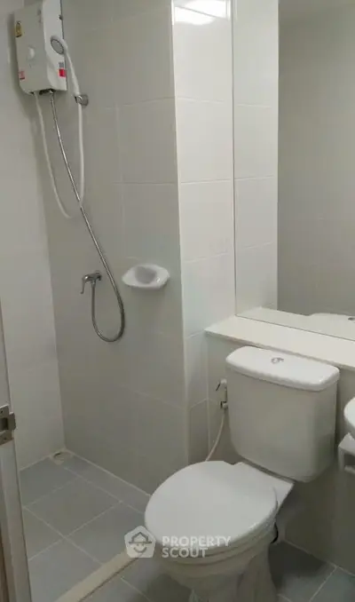 Modern bathroom with shower and toilet in sleek white tile design.
