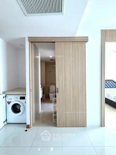 Modern apartment interior with washing machine and sliding door to bathroom