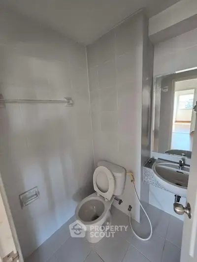 Compact bathroom with modern fixtures and white tiles, featuring a toilet and sink.
