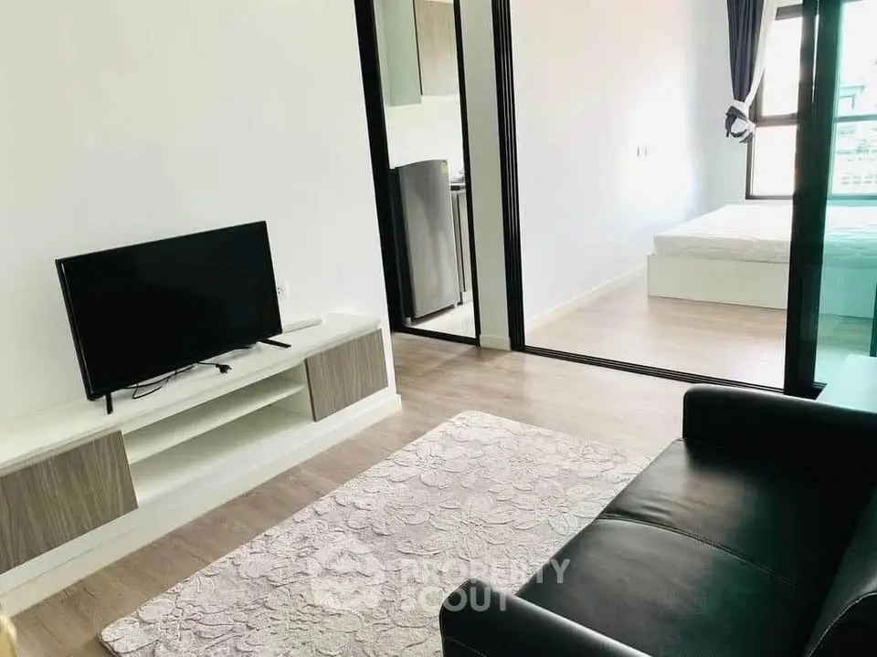 Modern living room with sleek design and natural light, featuring a cozy sofa and flat-screen TV.