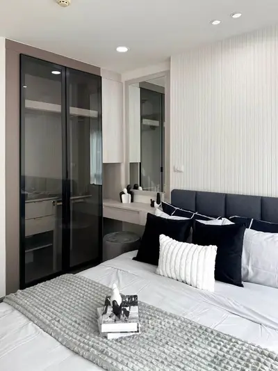 Modern bedroom with sleek design, featuring a stylish bed, elegant decor, and a built-in wardrobe with glass doors.