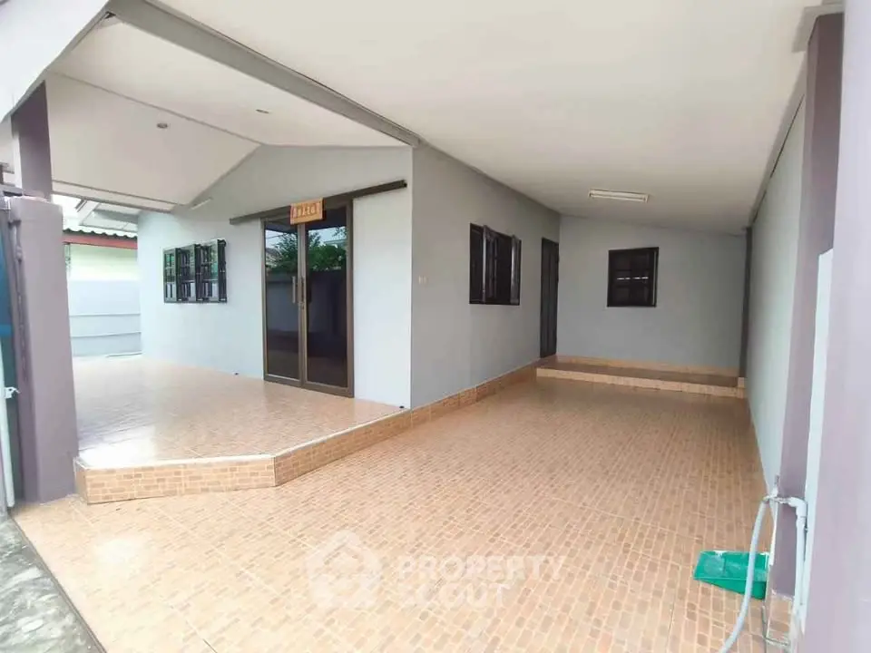 Spacious covered outdoor area with tiled flooring and modern design, perfect for versatile use.