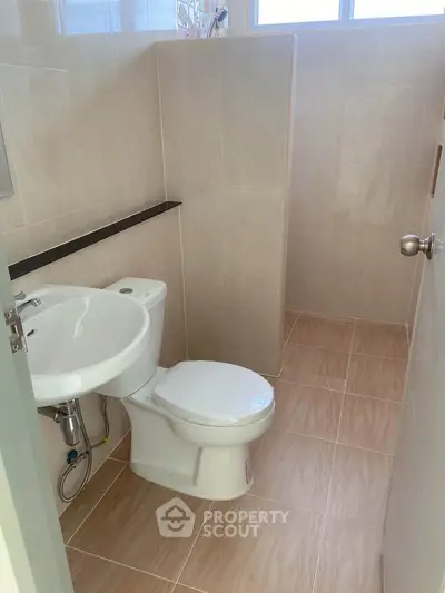 Compact bathroom with modern fixtures and neutral tiles