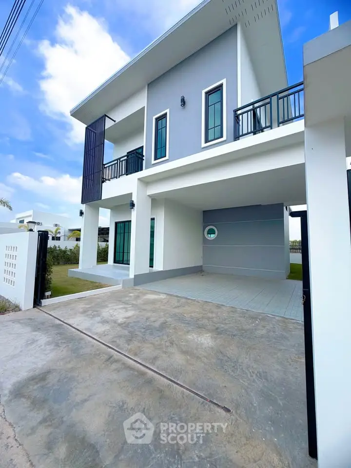 Modern two-story house with spacious driveway and sleek balcony design.