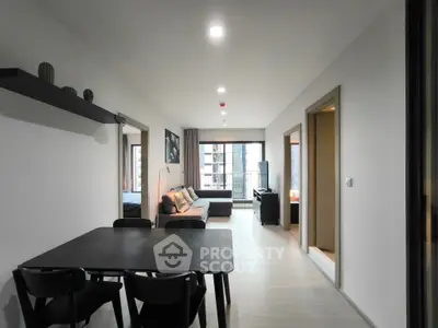 Modern apartment interior with open living and dining area, featuring sleek furniture and large windows.