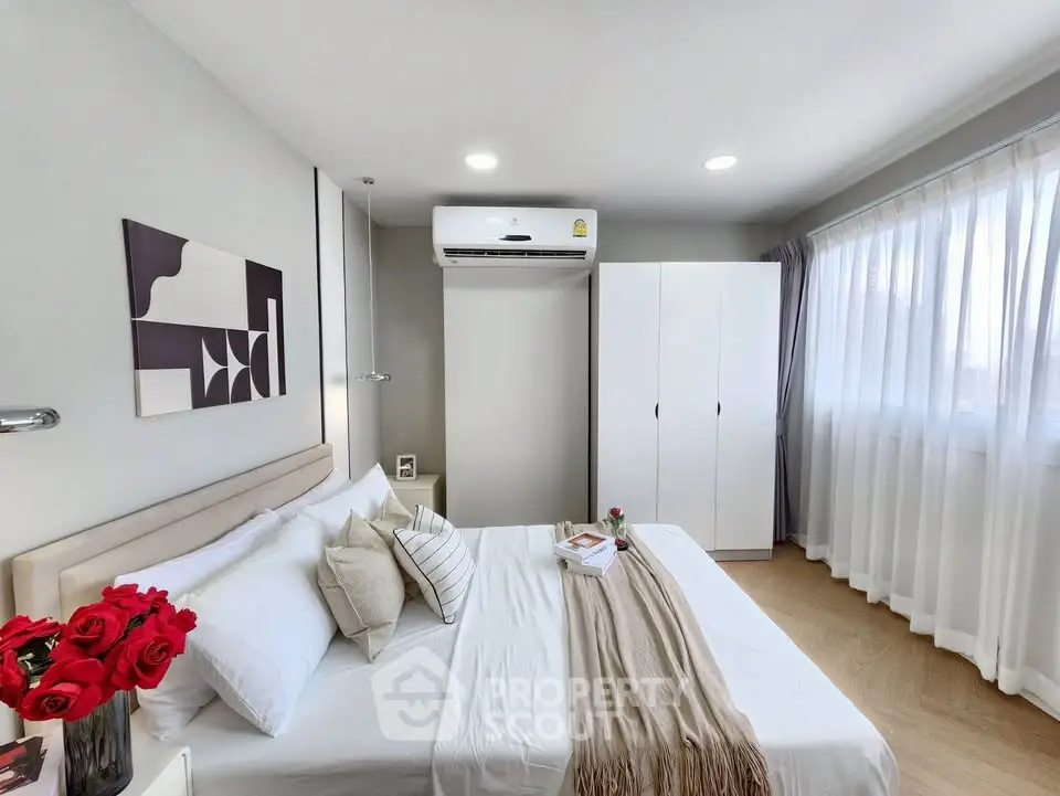 Modern bedroom with stylish decor, air conditioning, and natural light through large windows.