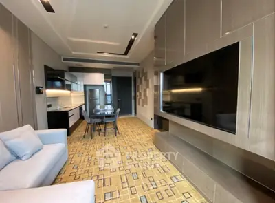 Modern living room with sleek design, large TV, and open kitchen layout in luxury apartment.