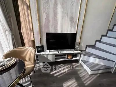 Modern living room with stylish decor and staircase, featuring a sleek TV setup and elegant dining area.