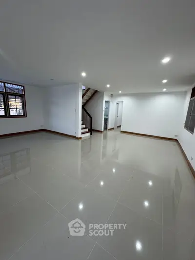 Spacious open-plan living room with glossy tiled floors and modern lighting.