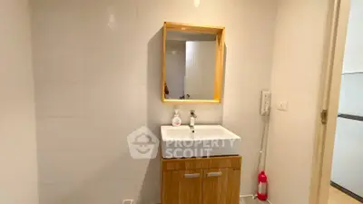 Modern bathroom with sleek sink and wooden cabinet, featuring minimalist design and neutral tones.