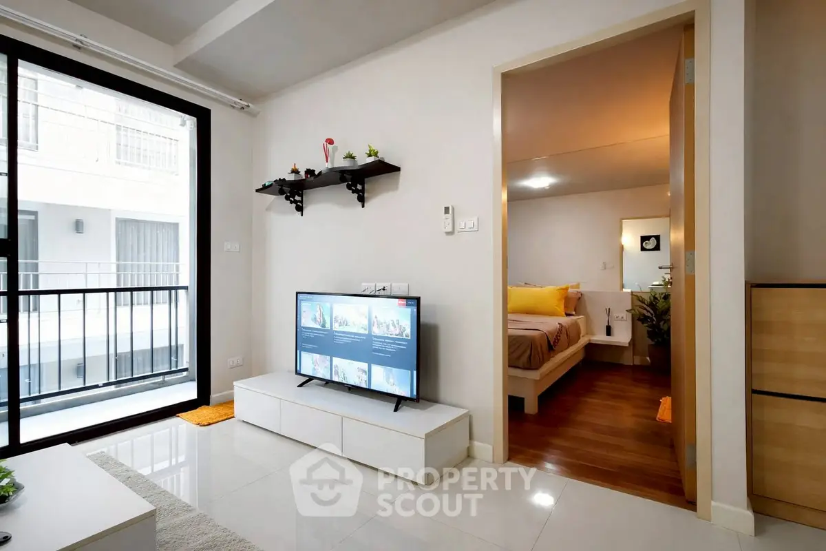 Modern apartment interior with open living room and bedroom, featuring sleek design and balcony access.
