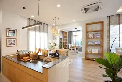 Modern open-plan living room with stylish kitchen and dining area, featuring elegant lighting and wooden flooring.