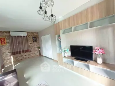 Modern living room with stylish shelving and TV, featuring brick accent wall and contemporary lighting.