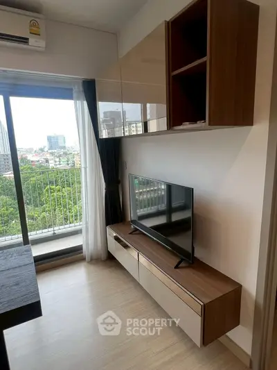 Modern living room with sleek TV unit and balcony view in urban apartment.