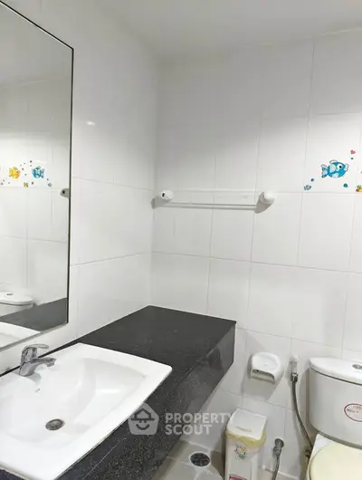 Modern bathroom with sleek sink and toilet, featuring white tiles and decorative accents.