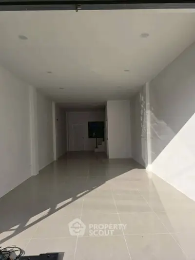 Spacious empty interior with white walls and tiled flooring, ideal for customization.