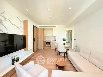 Modern living room with elegant furniture and open kitchen layout, featuring a sleek TV setup and stylish decor.