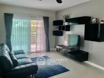 Modern living room with sleek black furniture and large window for natural light.