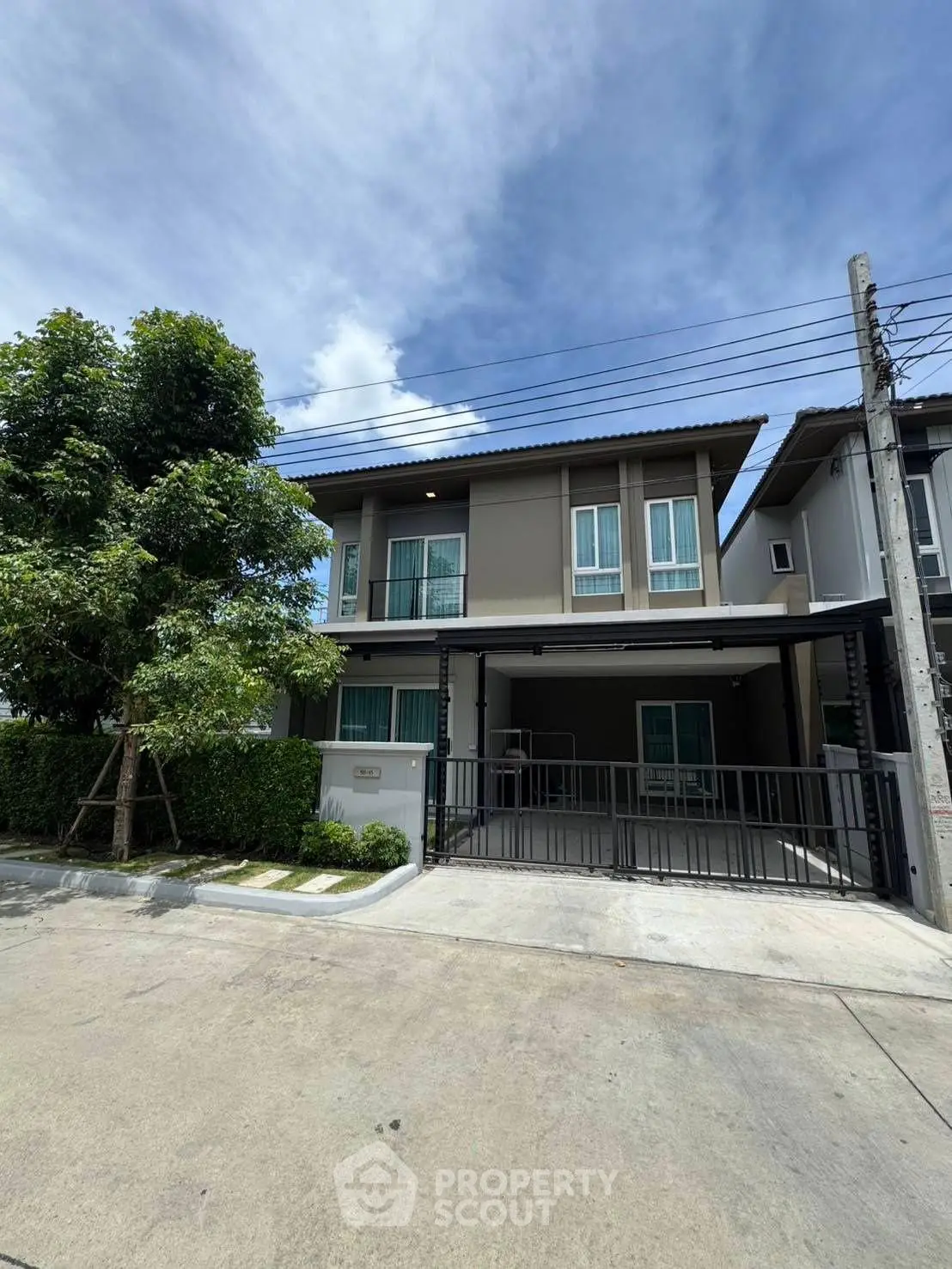 Modern two-story house with spacious driveway and lush greenery, perfect for family living.