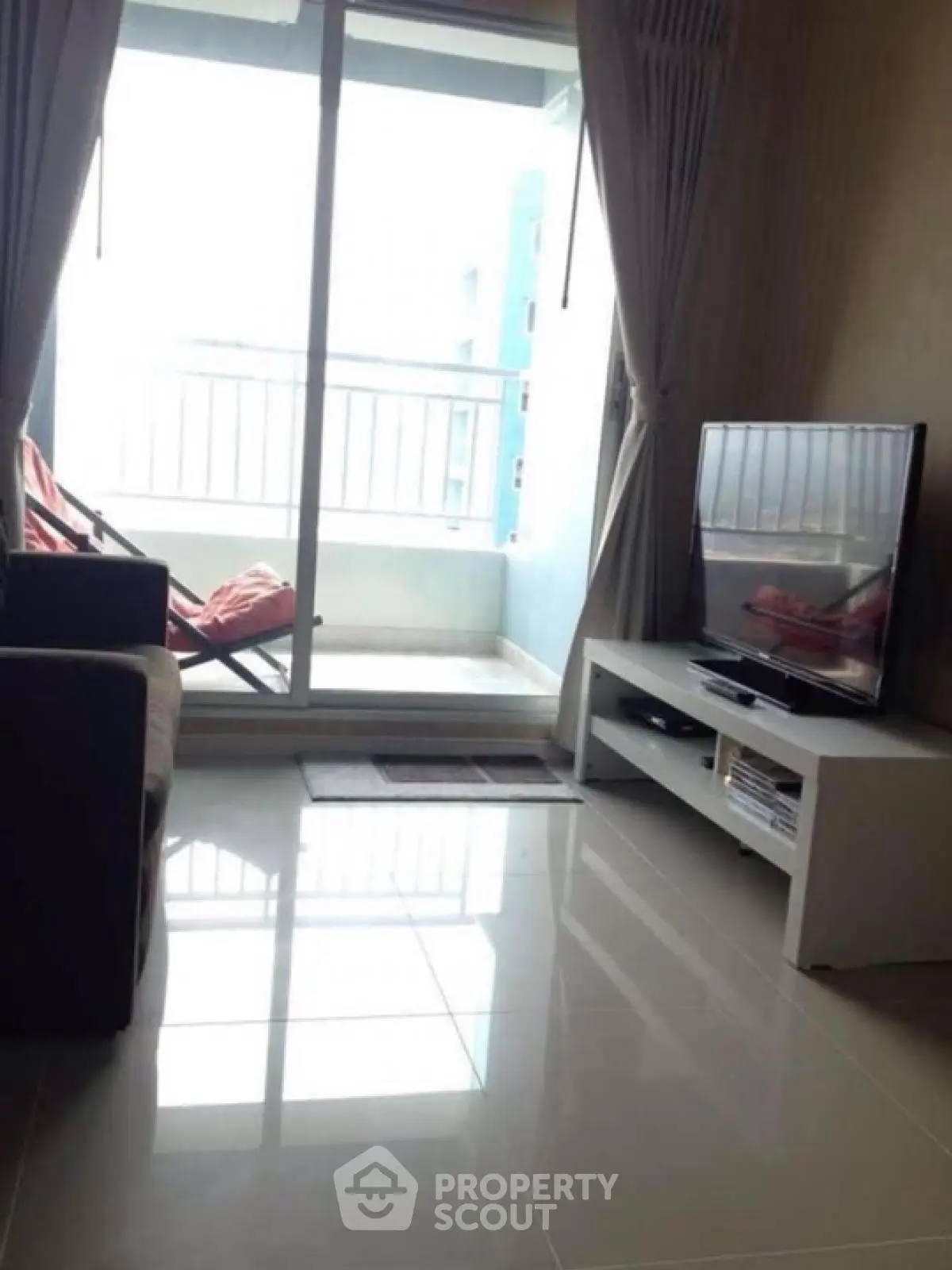 Modern living room with sleek TV setup and balcony view, perfect for urban living.