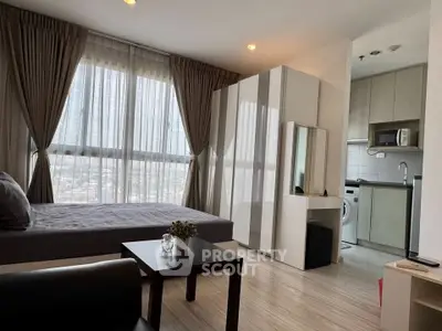 Modern studio apartment with large windows and compact kitchen in urban setting.