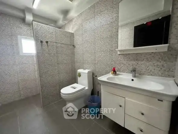 Modern bathroom with sleek fixtures and tiled walls, featuring a spacious layout.