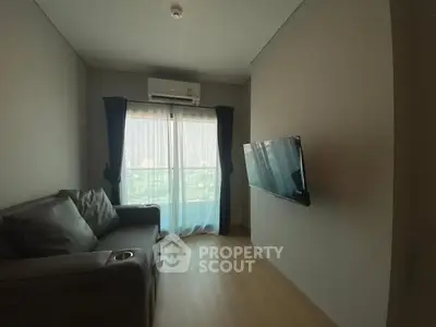 Cozy living room with modern sofa and wall-mounted TV, featuring large window with city view.